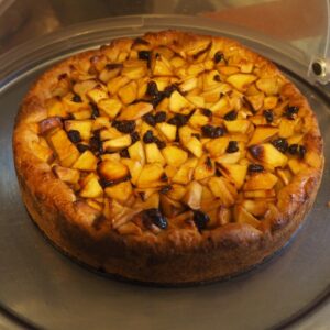 Tarte de maçã e passas assada com uma crosta dourada num tabuleiro redondo de metal