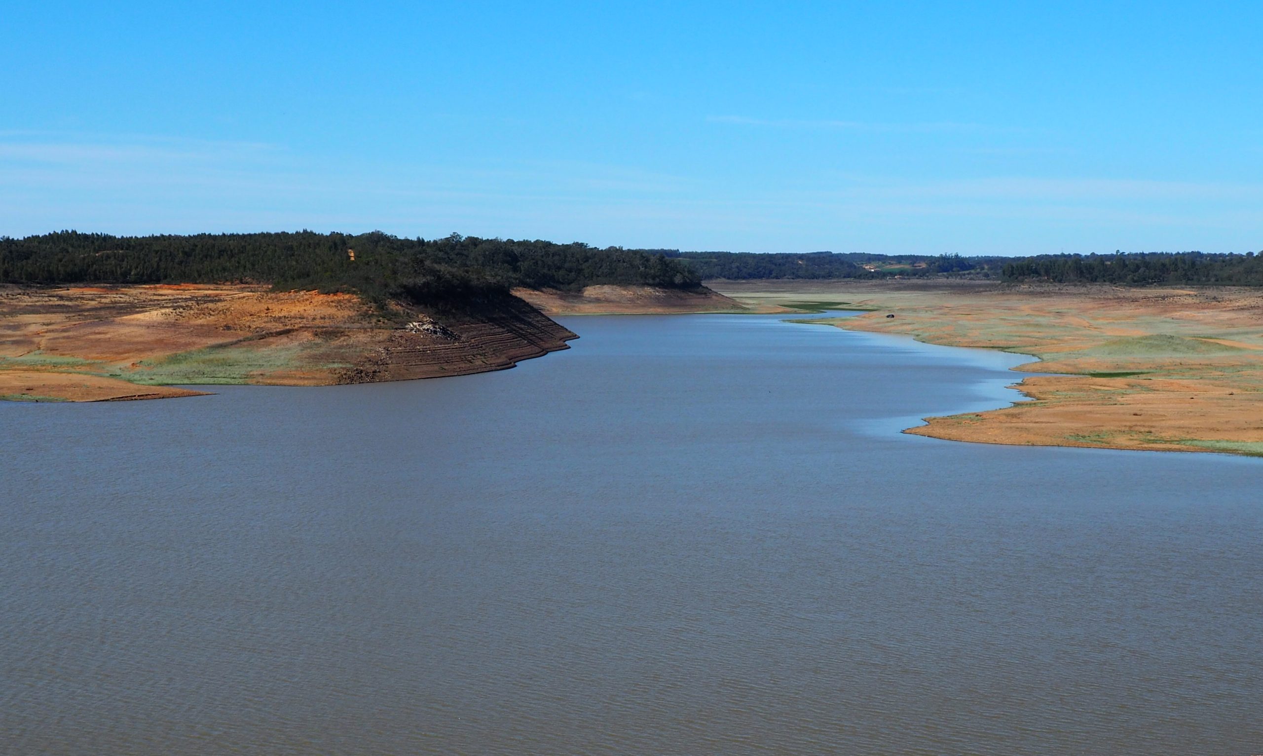 Embalse con unos niveles de agua extremadamente bajos, que deja al descubierto amplias riberas secas y áridas, así como marcas en forma de anillos de bañera en las laderas circundantes